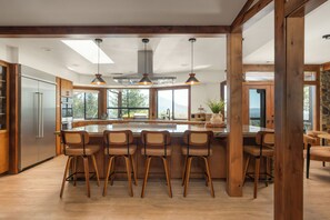 A modern kitchen with a central island, bar stools, and a large window offering a view of the outdoors. - Mountain Oasis, Sleeps 24, Hot tub, Game room (Oakhurst)