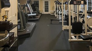 Une salle de sport équipée de tapis de course, d’appareils de musculation et d’une porte.