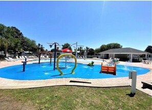 A swimming pool with a blue water feature, surrounded by a brick patio and a grassy area.