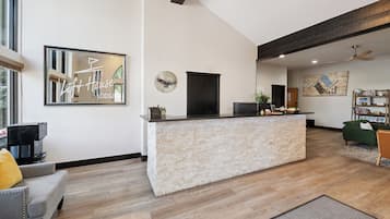 Een moderne woonkamer met een receptiebalie van steen, een grote spiegel en een groene bank.