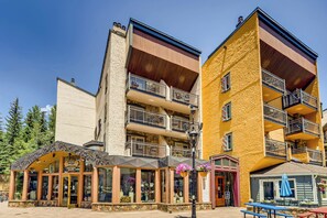 A multi-story building with balconies, a storefront with a sign, and outdoor seating. - Vail Mtn Views, 100m to Gondola | LH Studio (Vail)