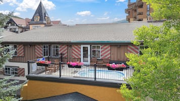 A building with a pool area, wooden benches, and flower planters.