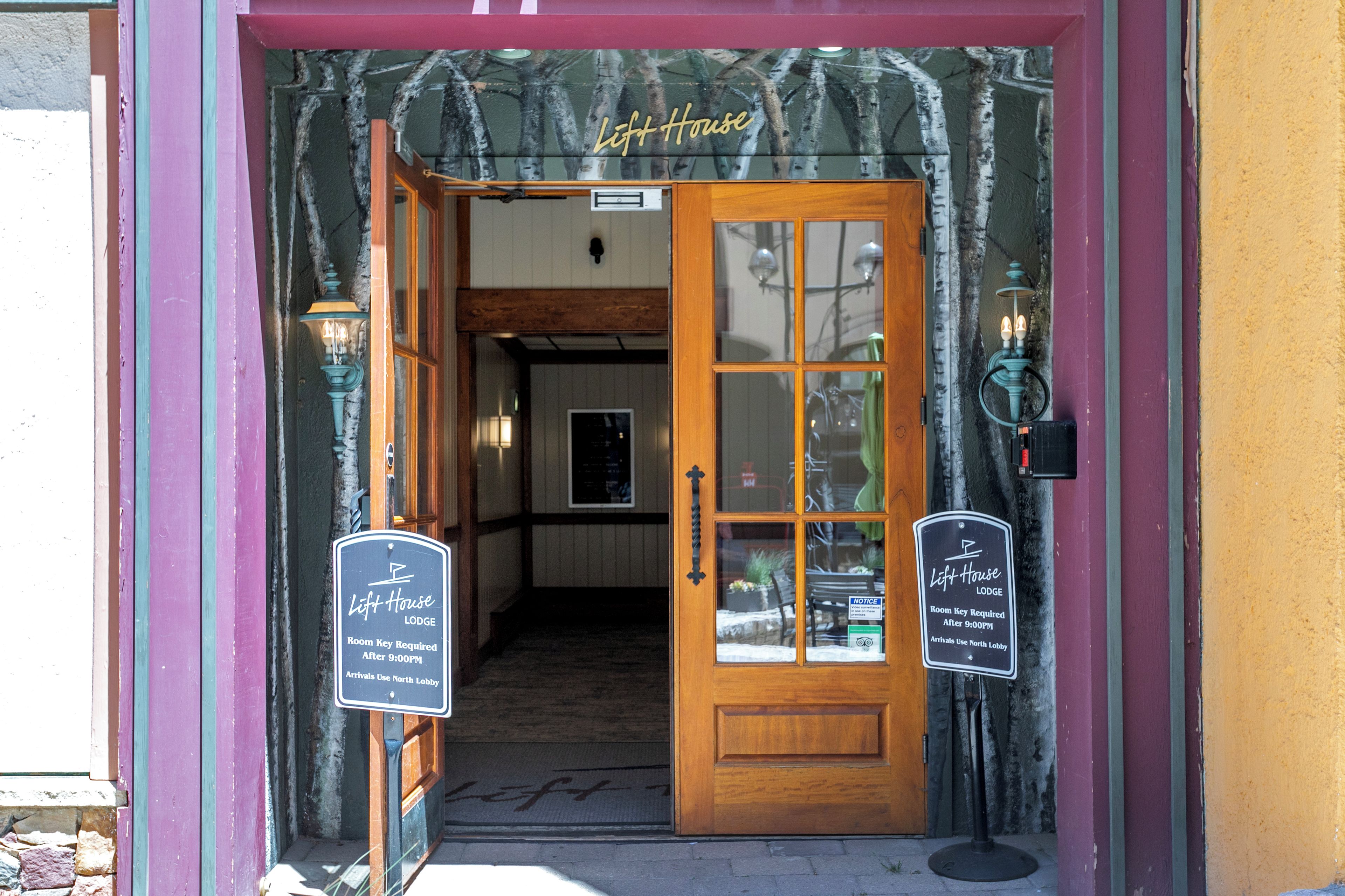 A wooden door with glass panels and a sign indicating it is the entrance to the Left House Lodge.