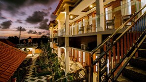 A multi-story hotel with a balcony on the upper floor, a staircase with a metal railing, and a checkered pathway leading to the entrance. - Nusa Sedayu hotel (Penida Island)