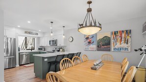 Una cocina moderna con armarios blancos, electrodomésticos de acero inoxidable y una mesa de comedor de madera con sillas.