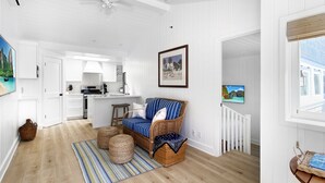 Amplia sala de estar con una isla grande, muebles de mimbre y un televisor montado en la pared.