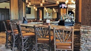 Un coin bar au style rustique, avec des chaises en bois et un mur en pierre.