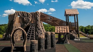 Une structure de jeu en bois, dotée d’un toboggan et d’éléments d’escalade.