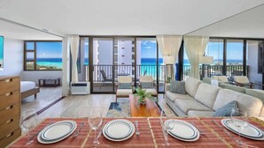 Une chambre d’hôtel avec un balcon, un coin repas aménagé pour quatre personnes et un canapé.