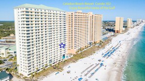 A high-rise hotel with multiple balconies overlooking a beach.