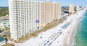 A high-rise hotel with multiple balconies overlooking a beach.