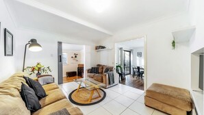A modern living room with a sofa, coffee table, and a dining area with chairs. - Seaward, Werri Beach - Gerringong (Werri Beach)