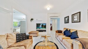 A modern living room with two leather sofas, a flat-screen TV, and a wooden coffee table. - Seaward, Werri Beach - Gerringong (Werri Beach)