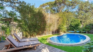 A backyard with a swimming pool, a wooden deck, and a lounge chair. - Seaward, Werri Beach - Gerringong (Werri Beach)