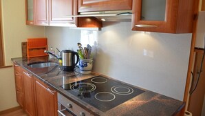 Una cocina con armarios de madera, un hervidor de acero inoxidable, una cafetera y un especiero.