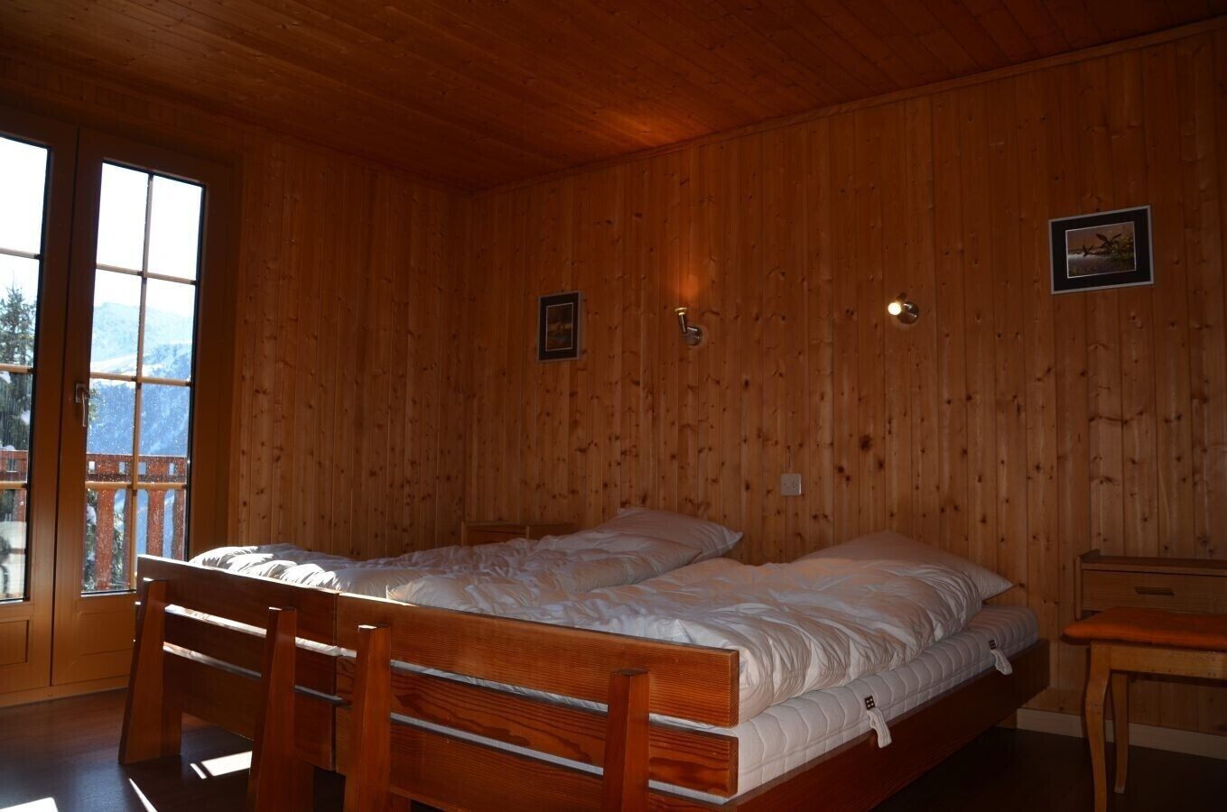 Una habitación con paneles de madera, una cama, una silla y una mesita.