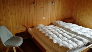 Una habitación con paneles de madera, una cama, un sillón y una mesita de noche.
