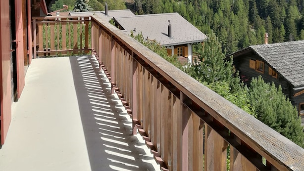 Un balcón de madera con vistas a una montaña boscosa.