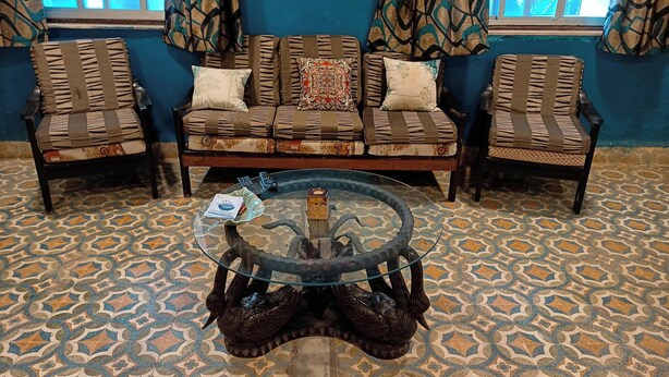 A living room with a sofa set, two armchairs, and a glass coffee table with remote controls. - Beautiful colonial Rowhouse with 2000 sqft Pvt garden, Lonavala (Lonavla)