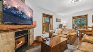 Una sala de estar acogedora con chimenea, sofá de cuero y un televisor de pantalla plana colgado en la pared.