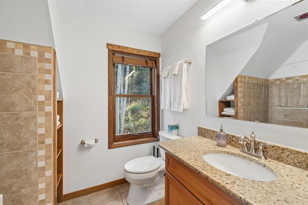 A bathroom with a toilet, sink, and window.