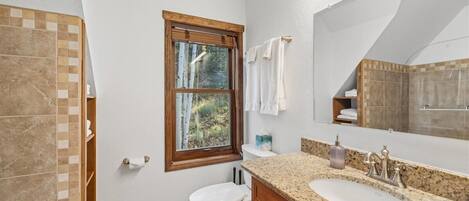 A bathroom with a toilet, sink, and window.