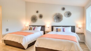 A hotel room with two beds, a ceiling fan, decorative wall art, and bedside lamps. - Americas Best Value Inn Ocean Shores (Ocean Shores)