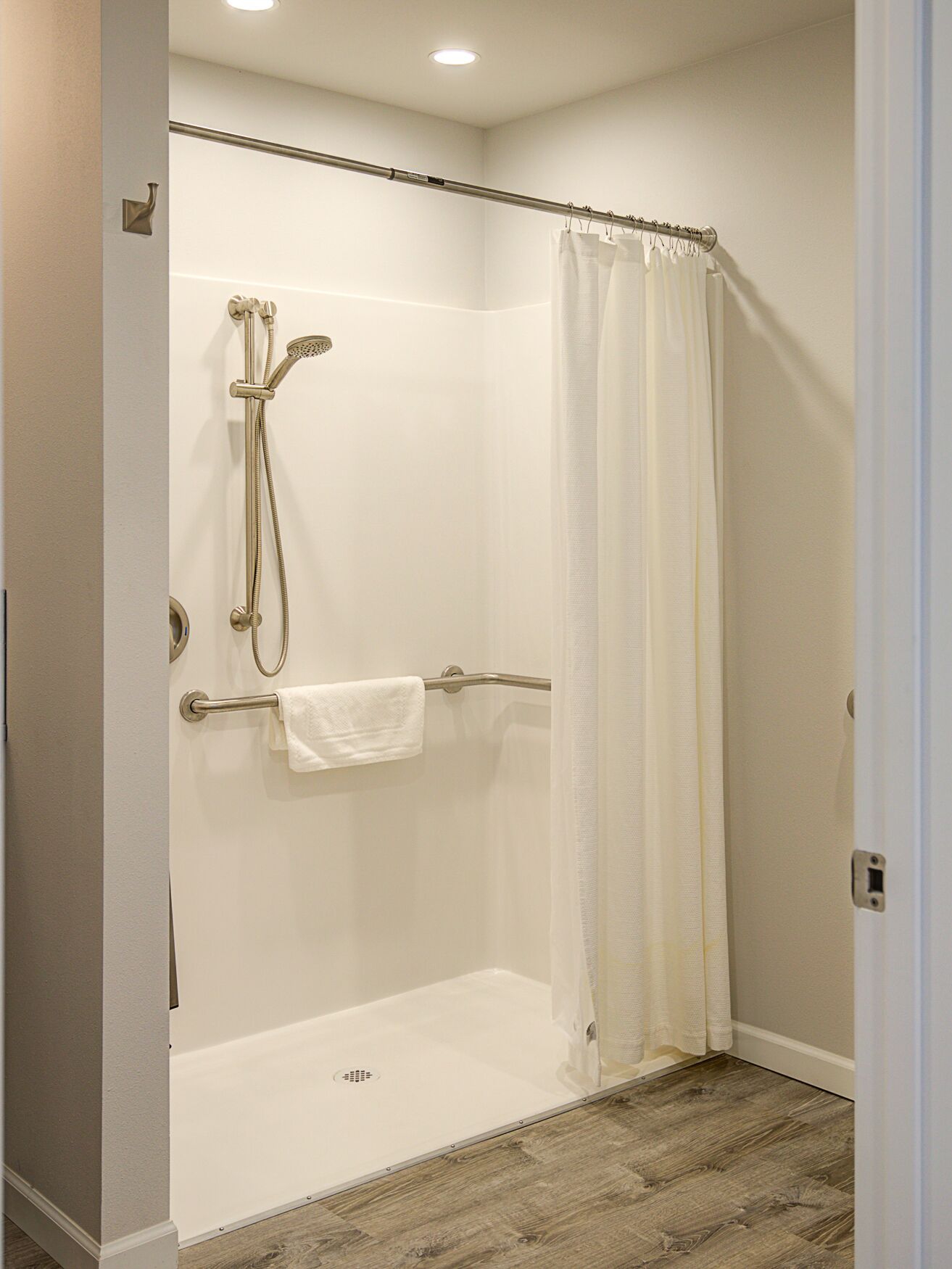 A walk-in shower with a glass door, a towel rack, and a showerhead.