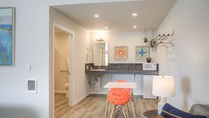 A modern kitchen with a central island, a dining area with a table and chairs, and a living area with a sofa and a lamp. - Americas Best Value Inn Ocean Shores (Ocean Shores)