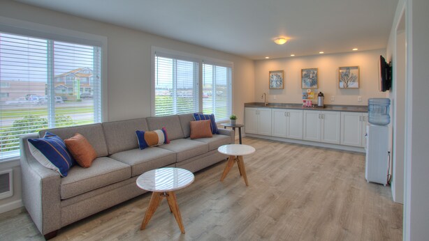 A spacious living area with a sofa, two round tables, and a kitchen in the background. - Americas Best Value Inn Ocean Shores (Ocean Shores)