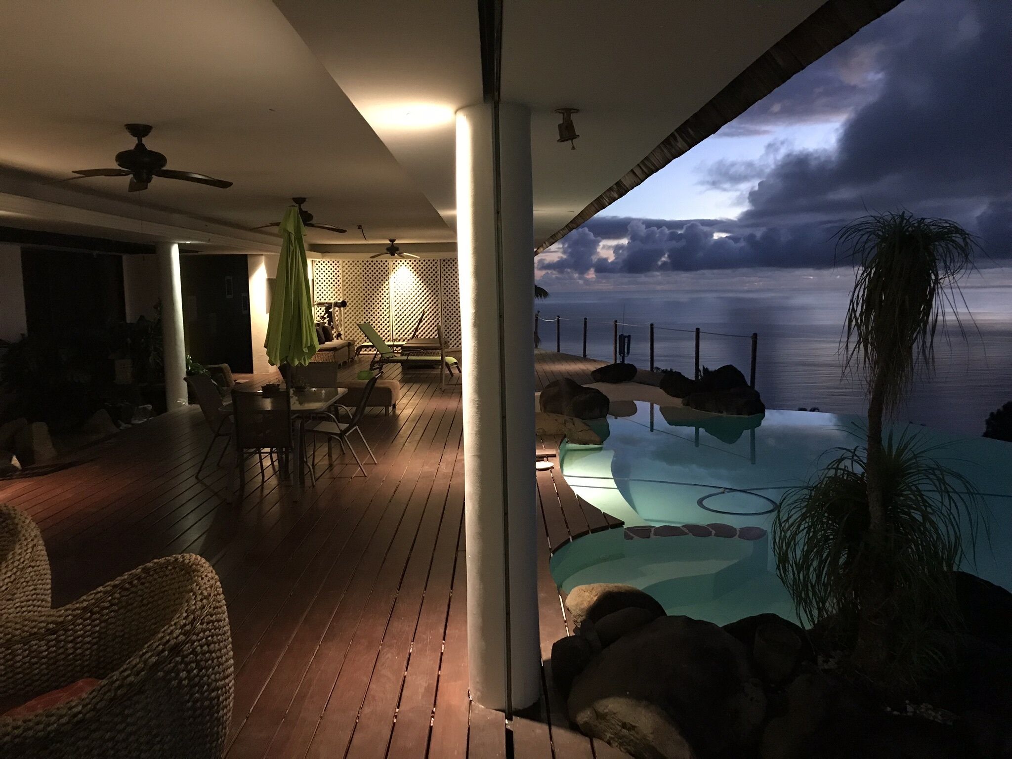 An outdoor deck with a pool, seating area, and a view of the sea.
