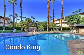Relax by the pool surrounded by palm trees and lounge chairs in the Condo King's tranquil outdoor space.