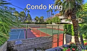 Enjoy a tennis match in a serene setting surrounded by lush greenery and secure fencing.