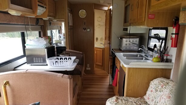 A compact RV kitchen with a stove, sink, and a small refrigerator. - RV/Motor Home by LAVENDER FARM! Free HIGH SPEED BEST INTERNET=WORK from HOME W/D (Sequim)