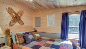 Une chambre à coucher dans une cabane en bois, avec un lit, une carte accrochée au mur et une fenêtre avec des rideaux.