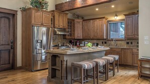 A kitchen with wooden cabinets, stainless steel appliances, a granite countertop, and a bar stool seating area. - Stunning W/Mountain Views + Hot Tub + Close to Skiing - Overlook Chalet (Steamboat Springs)