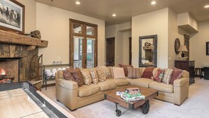 A cozy living room with a sectional sofa, a fireplace, and a coffee table with board games. - Stunning W/Mountain Views + Hot Tub + Close to Skiing - Overlook Chalet (Steamboat Springs)