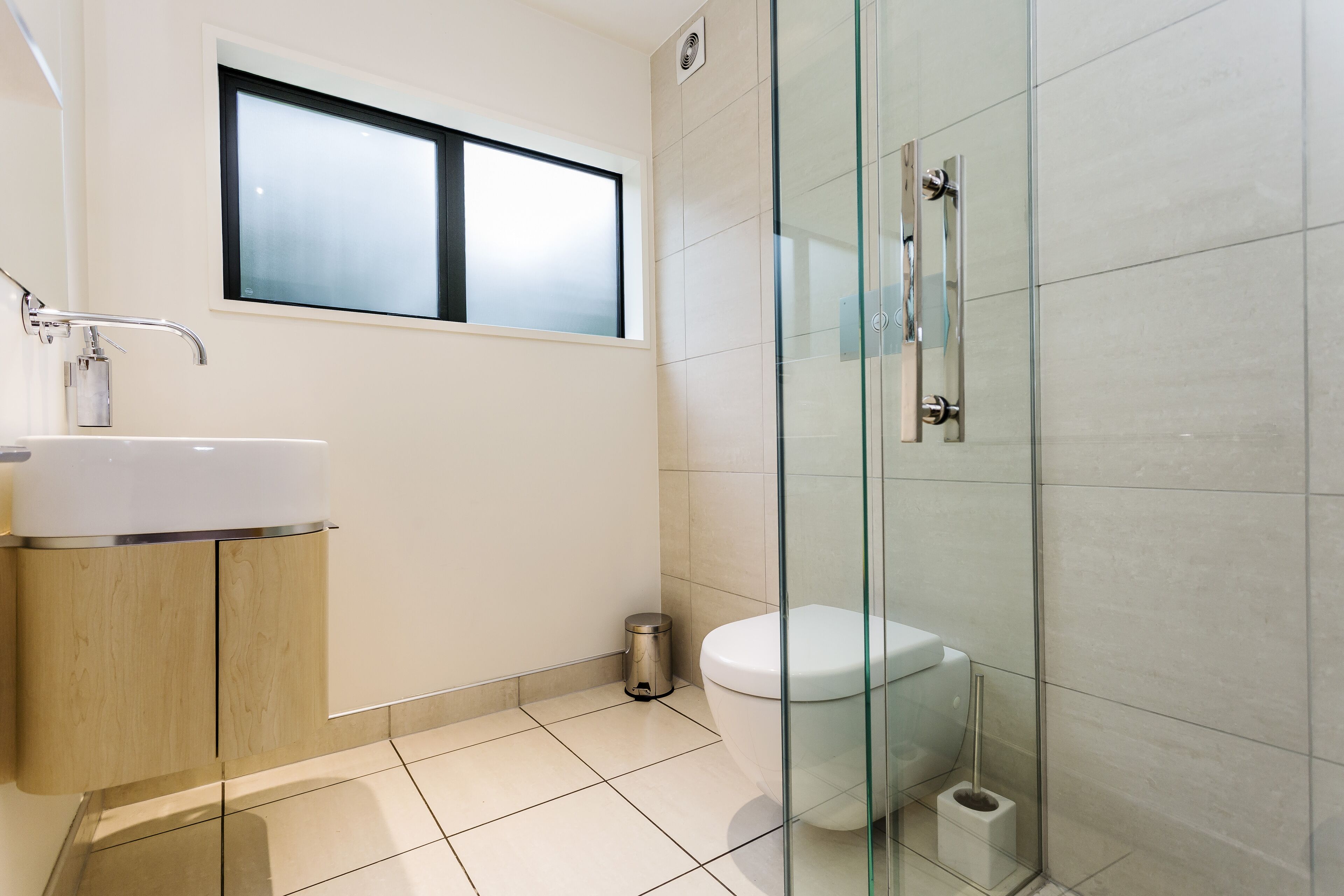 A modern bathroom with a glass shower enclosure, a white sink, and a toilet.