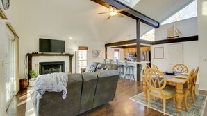 A spacious living room with a fireplace, a dining area with wooden chairs, and a kitchen in the background. - Furnished Porch! Margaritaville Resort Family Stay (Osage Beach)