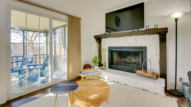A living room with a fireplace, a television mounted above it, and a large sliding glass door leading to an outdoor area with chairs. - Furnished Porch! Margaritaville Resort Family Stay (Osage Beach)