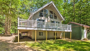Une cabane à deux étages dotée d’un balcon, entourée d’arbres.