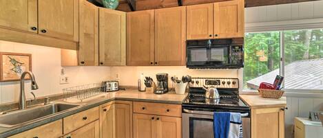 A kitchen with wooden cabinets, a stainless steel stove, a microwave, and a sink.