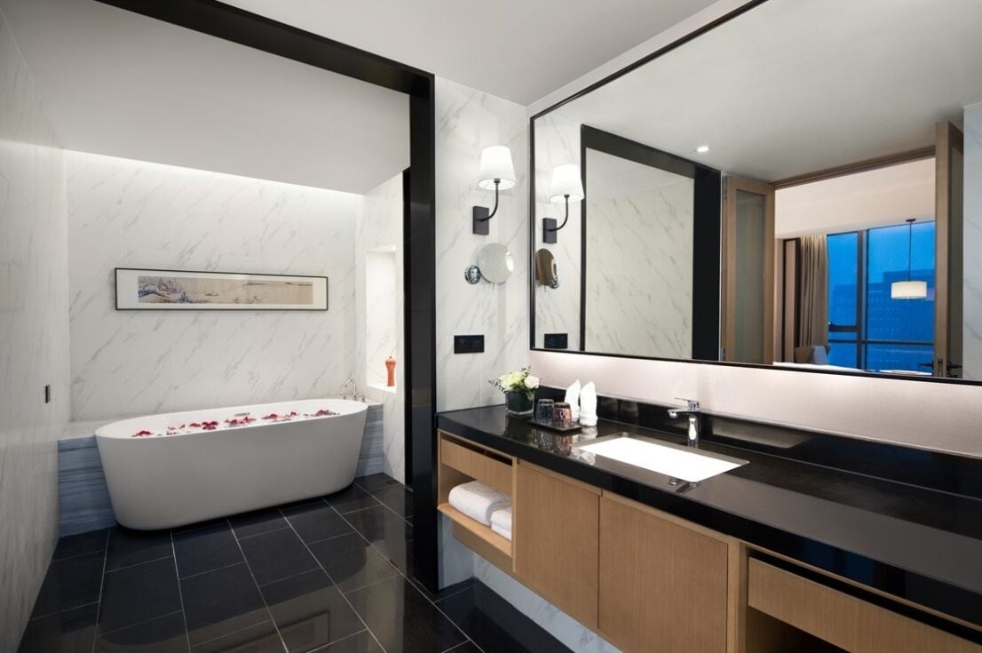 Une salle de bain moderne avec une baignoire sur pieds, un grand miroir et un meuble-lavabo à plateau noir.