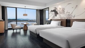 Habitación de hotel con dos camas, televisión, escritorio y vista a un cuerpo de agua.