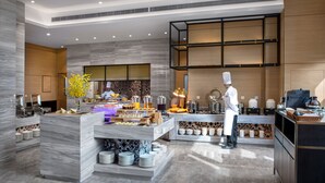 Una cocina moderna con encimeras de mármol, un chef preparando comida y una mesa de buffet.