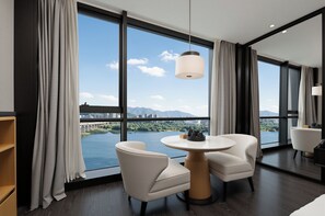 A modern hotel room with a large window, two white chairs, a round table, and a hanging light fixture. - Yiho Hotel (Fuzhou South Railway Station)  (Fuzhou)
