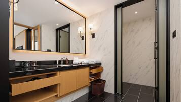 Une salle de bain moderne avec un grand miroir, un plan de toilette noir, des meubles en bois et une porte de douche en verre.