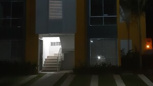 Ein Gebäude mit einer Treppe, die zu einem Eingang führt, umgeben von einem gepflegten Rasen.