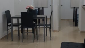 Ein Essbereich mit Tisch und Stühlen, einer schwarzen Couch und einer Blumenvase.