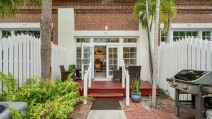 A residential property with a brick facade, numbered 22, featuring a front porch with wicker furniture, a barbecue grill, and a potted plant. - **CARIBBEAN CHARM** Villa Near Duval & Beach + Last Key White Glove Service... (Key West)